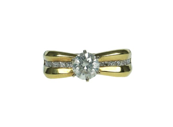 yellow gold bow style eighteen karat engagement style ring with center round brilliant cut diamond one point ten carats and enhanced with a total of eighteen princess cut diamonds approximately zero point zero three carats each